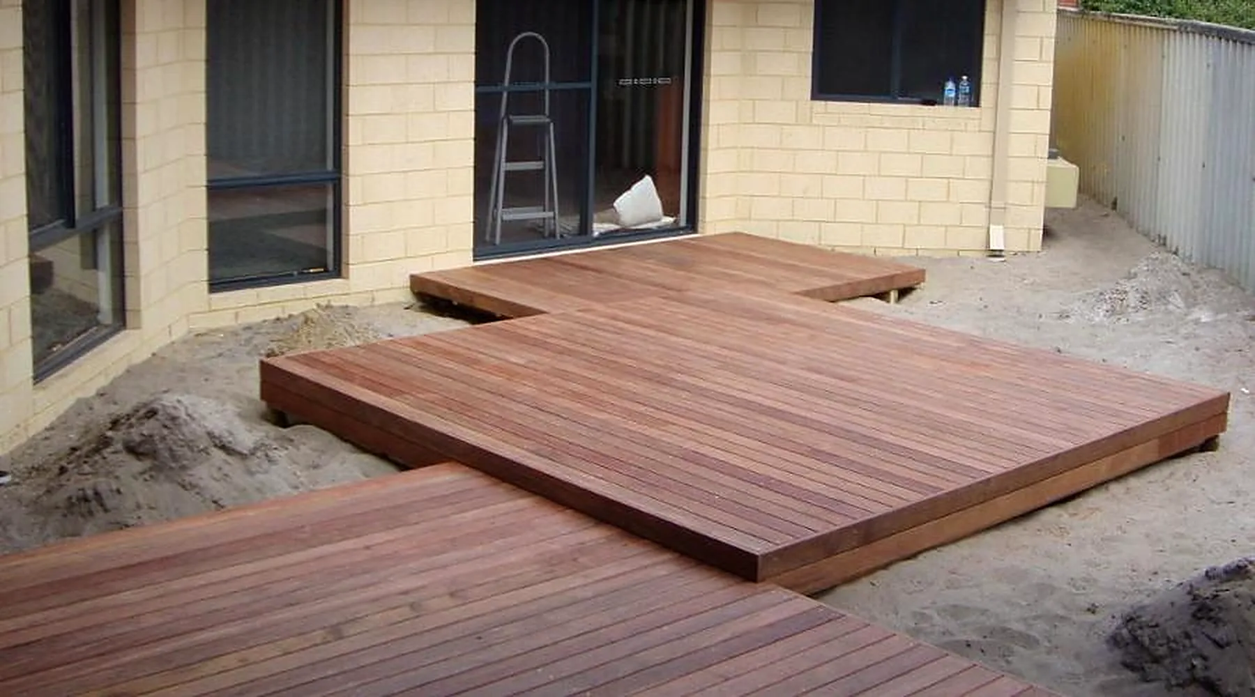 Stepped multi-level hardwood deck platforms outside a cream brick home